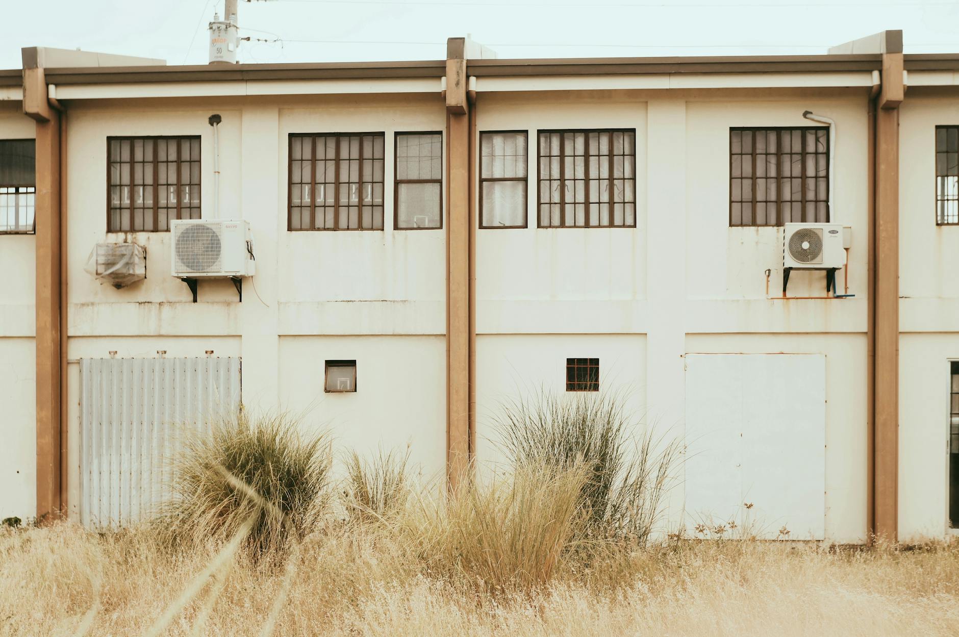 Facade of an urban industrial building with large windows and air conditioning units.
