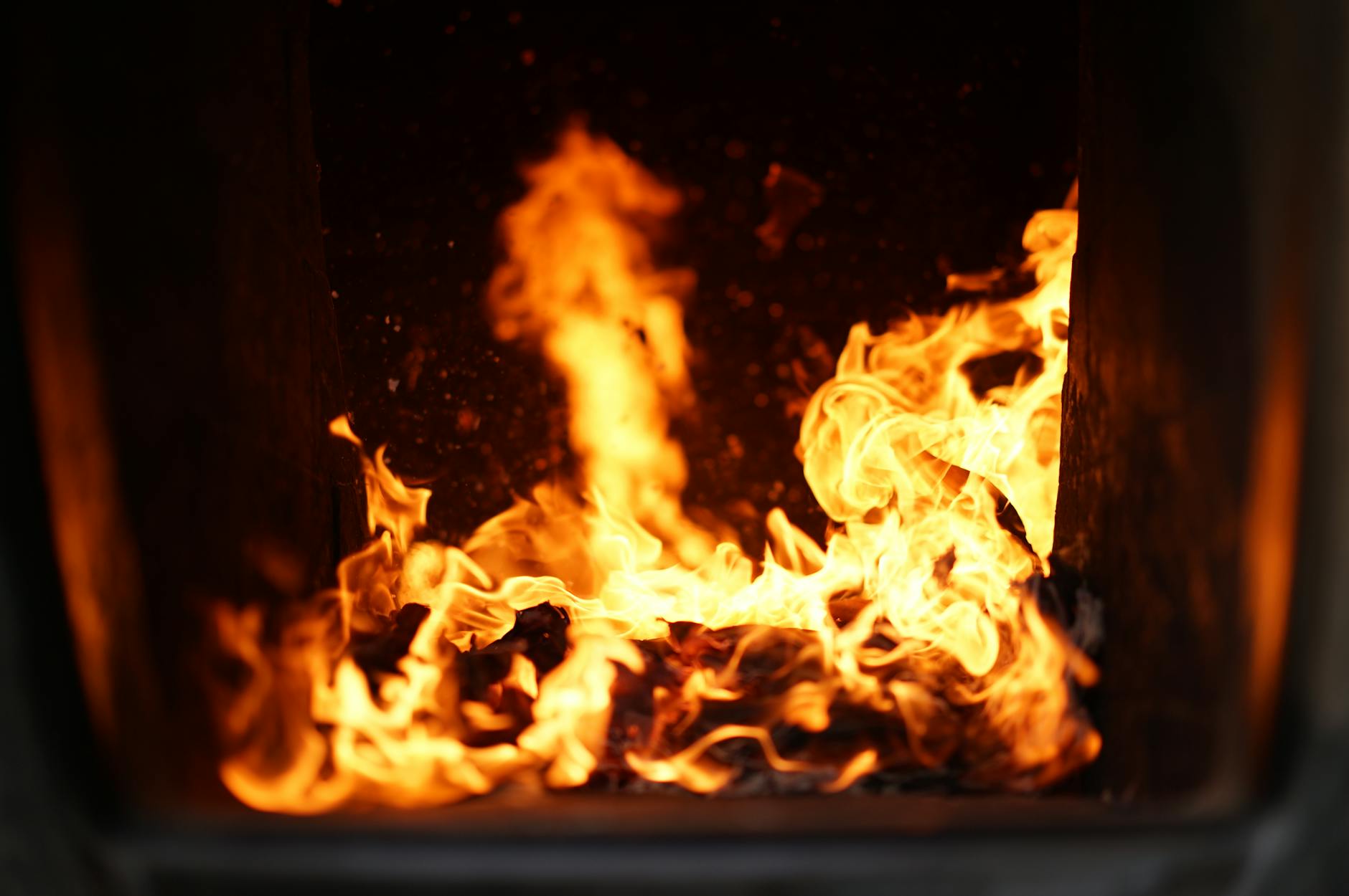 Bright flames in a dark furnace create a warm, vibrant atmosphere.
